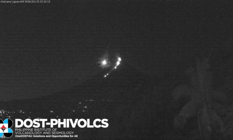 Moment meteor flies through sky beside erupting volcano