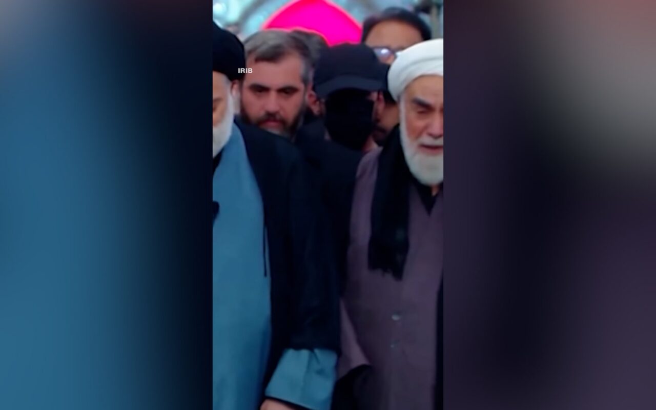 قبعة سوداء وقناع يثيران تساؤلات.. من هو الغامض الذي لفت الأنظار بجنازة خامنئي؟