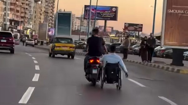 الجدعنة في أبهى صورها .. شاب يساعد صديقه على كرسي متحرك ويخطف قلوب المصريين