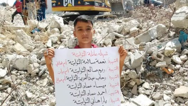 طفل فلسطيني يحمل ورقة عليها أسماء 10 من أفراد أسرته استشهدوا تحت أنقاض منزلهم في غزة