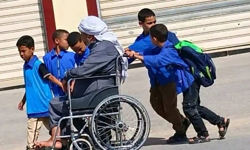 أطفال يساعدون شيخاً مقعداً في الجزائر.. صورة تتصدر “الترند”